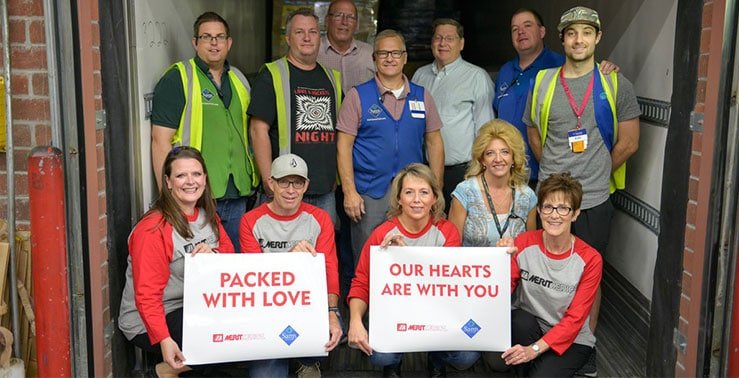 一群优秀员工举着写有“充满爱”和“我们的心与你同在”的牌子。