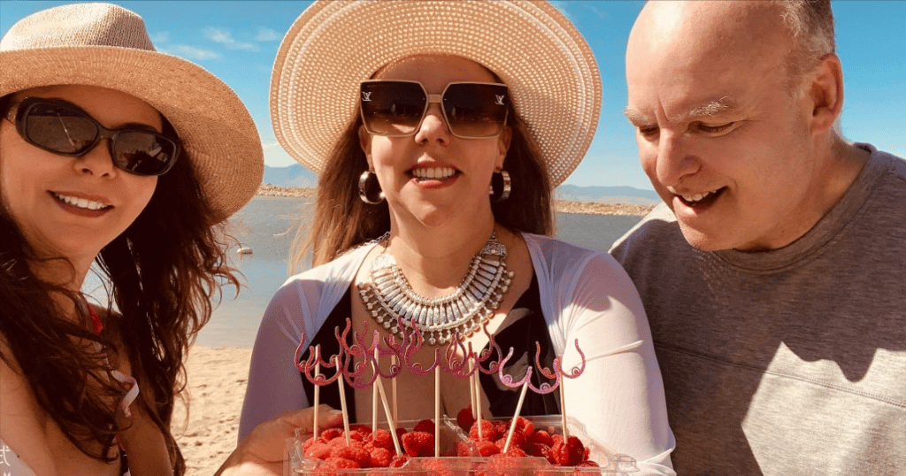 两名妇女和一名男子在海滩上摘水果，庆祝中间的妇女摆脱了乳腺癌